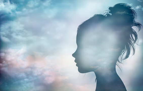 Concept of thinking - psychology - imagination - intelligence or inspiration.Character and personality metaphor.Woman face profile silhouette with sky and clouds background.Mental disorder