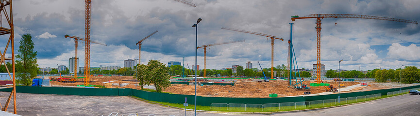 Obraz premium View of New Mass Construction Site with Macines and Cranes Against Sky with Clouds.
