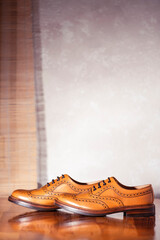 Pair of Full Broggued Tan Leather Oxfords Broggued Shoes Against White Wall Background