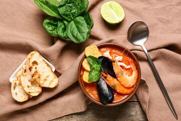 Bowl of tasty Cacciucco soup with spinach and bread on wooden background