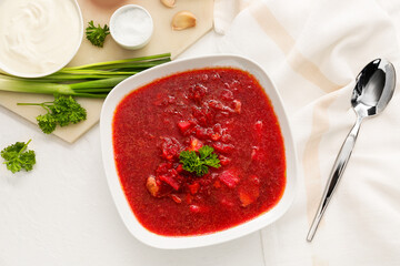 Bowl with tasty borscht, sour cream and green onion on light background