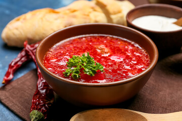 Bowl with tasty borscht on color background