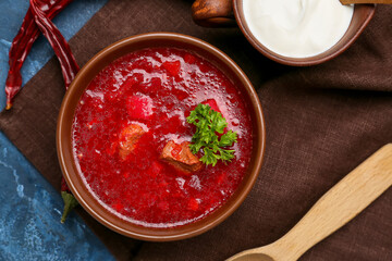 Bowl with tasty borscht and sour cream on color background