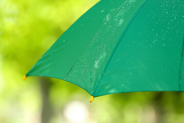 Open umbrella with rain drops outdoors