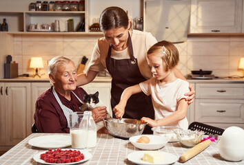 Woman hugging child and granny by shoulders while cooking