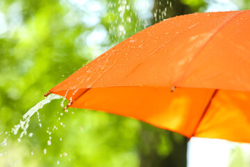 Open umbrella under falling rain drops outdoors