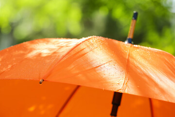 Open umbrella with rain drops outdoors