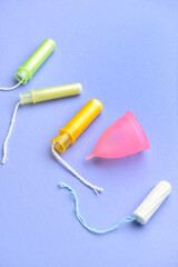 Tampons and menstrual cup on color background