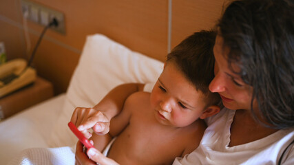 Happy young mother with little son using smart phone together