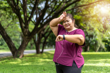 Fat woman asian checking time or heart rate from smart watch. Exercise outdoors for weight loss idea concept With