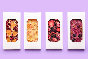 Handmade chocolate bars with fruits and berries on color background