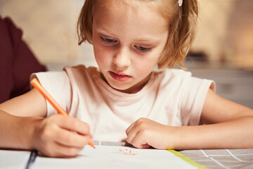 Concentrated kid using orange marker for painting picture