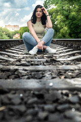 pretty young woman is standing near the railway tracks