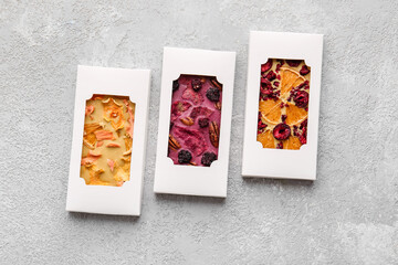 Handmade chocolate bars with fruits and berries on grey background