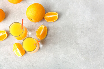 Glasses of tasty orange juice on light background