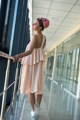 Young lady inside long corridor posing in pink glamour dress