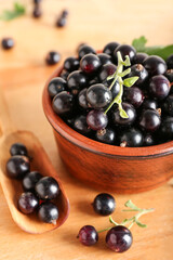 Bowl and scoop with ripe black currant on wooden background, closeup