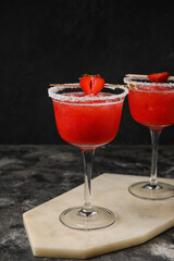 Glasses of tasty strawberry margarita on dark background