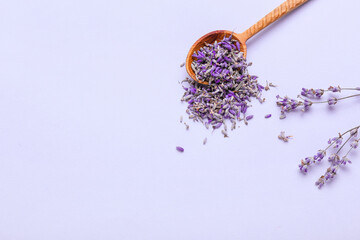 Spoon with lavender flowers on color background
