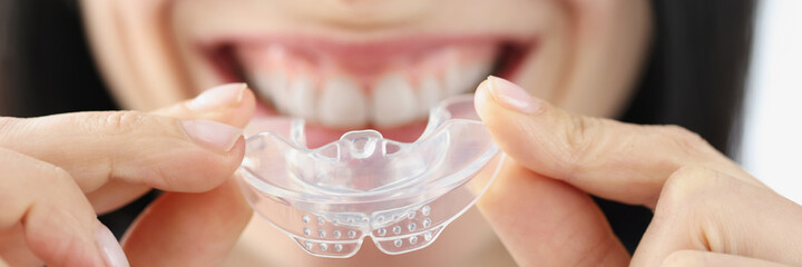 Smiling woman holding plastic mouth guard for teeth whitening