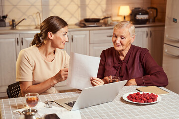 Female holding document and letting elderly woman have a look