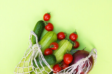 Ripe juicy red tomatoes, green cucumbers and zucchini in a string bag.