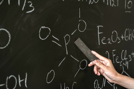 chemistry teacher writing and explane chemical formula on class board