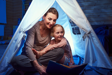 Mother and daughter sitting in tent in bedroom