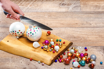 human hand grinds christmas baubles by knife on wooden surface. Cooking or prepare Christmas,...