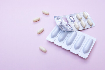 Gynecological medicines for women's health in form of suppository, capsules on pink background.