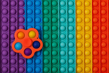 Trendy toy spinner Simple Dimple on multi-colored surface POP IT. Tap on bubble, finger game