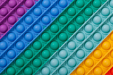 Surface of multi-colored rubber children's toy POP IT, close-up. Tap on bubble, finger game.