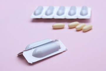 Gynecological medicines for women's health in form of suppository, capsules on pink background.
