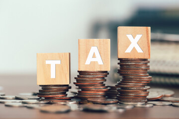 Tax concept with Wooden cubes with the word Tax on stacked coins