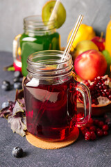 Mason jars with healthy juice, fruits and vegetables on dark background