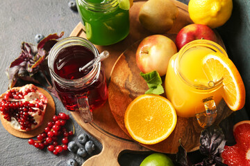 Mason jars with healthy juice, fruits and vegetables on dark background
