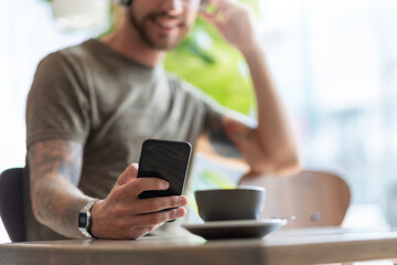 Smiling man using smartphone at cafe.