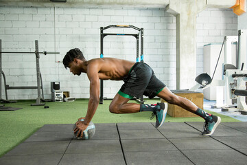 young african american man doing push-ups with a ball in the gym