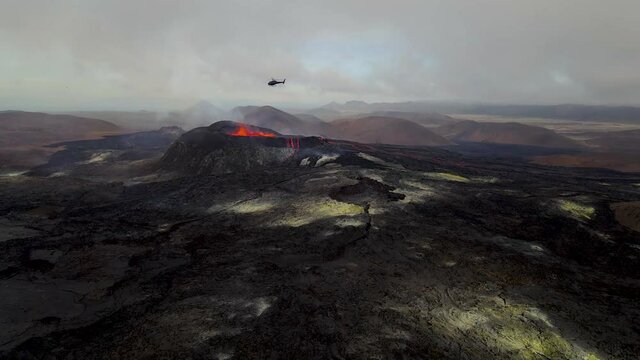 Beautiful aerial cinematic footage of the bowling lava exploding from the Active Volcano and a helicopter  in Iceland