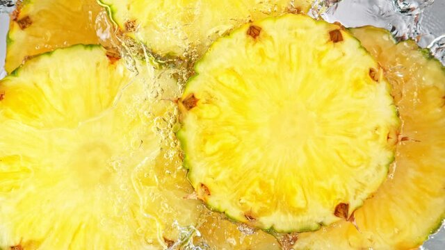Super Slow Motion Shot of Splashing Fresh Pineapple Slices into Water at 1000 fps.