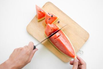 Top view hand holding knife cut slice watermelon on wooden chopping board with white table....