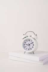 Naklejka premium White alarm clock on stack of books, mockup design