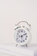 White alarm clock on stack of books, mockup design