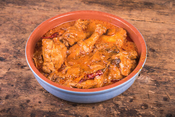 Hungarian chicken stew with paprika and sour cream - chicken paprikash in a clay bowl on a wooden table, close-up