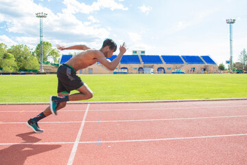 African American muscular young man running on running track