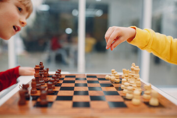 Little kids playing chess at kindergarten or elementary school. Children's chess play