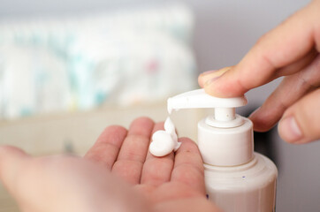 Man's hands holding body lotion bottle and using cream for baby body.