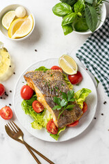 Top view of prepared delicious halibut fish steak with salad on white plate. Healthy food rich of omega unsaturated fats good for brain health