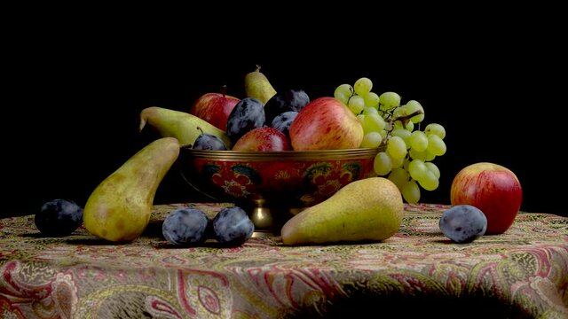 Still life with fruits on a black background. pears, grapes, apples, plums