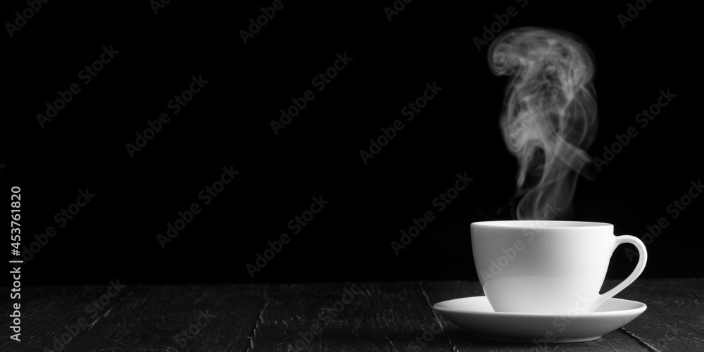 Wall mural hot coffee on the table on a black ackground